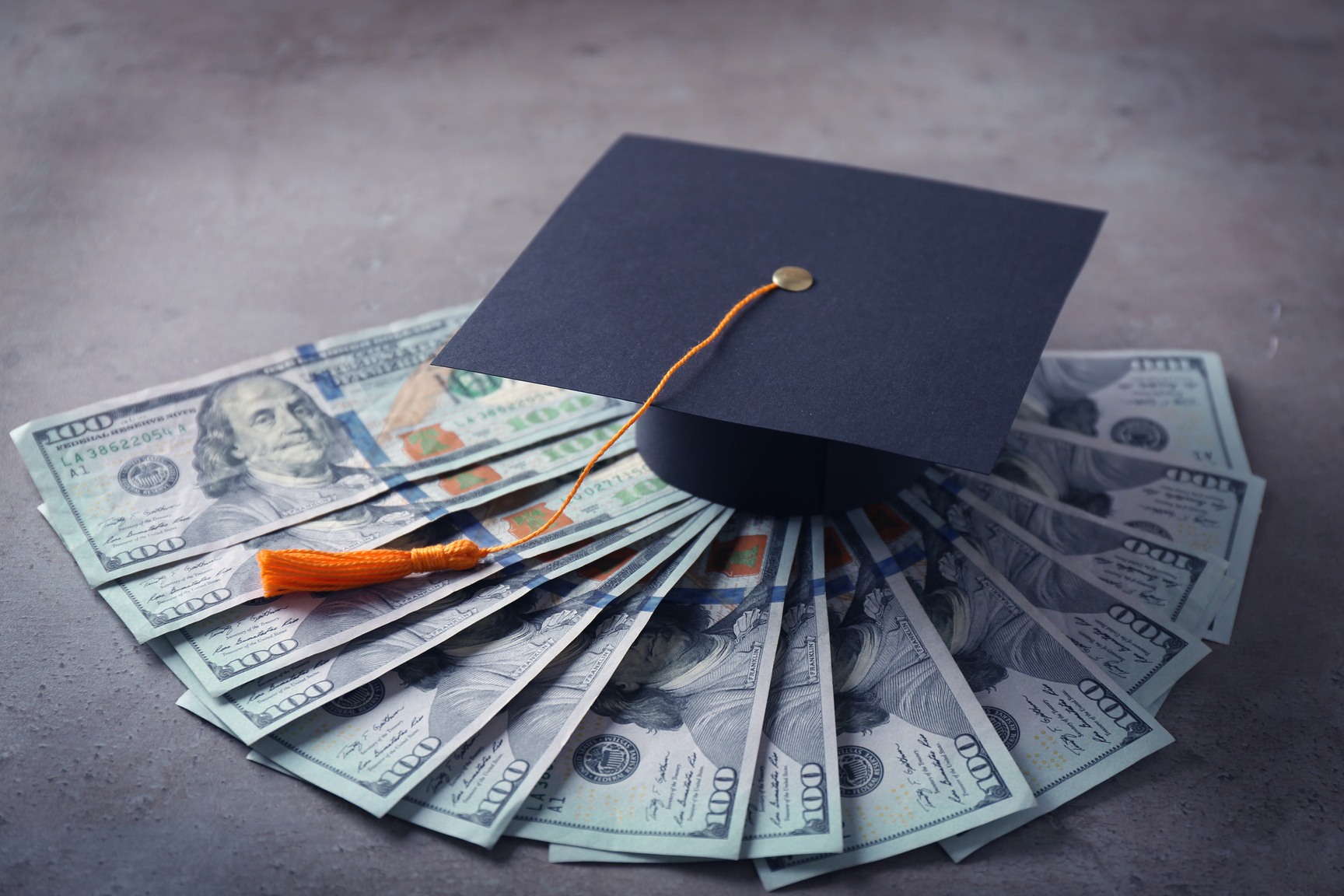 Graduation Hat and Dollar Banknotes on Table
